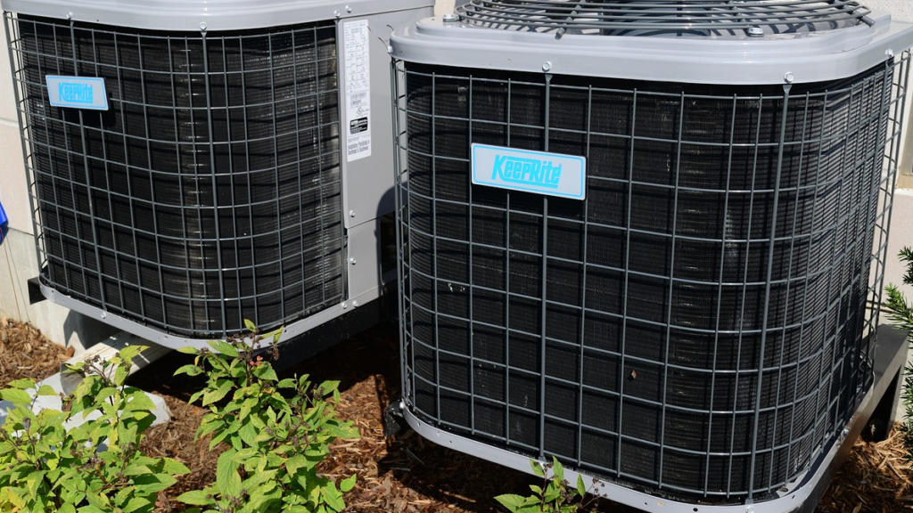 Two KeepRite brand air conditioning units installed outdoors, surrounded by plants and mulch